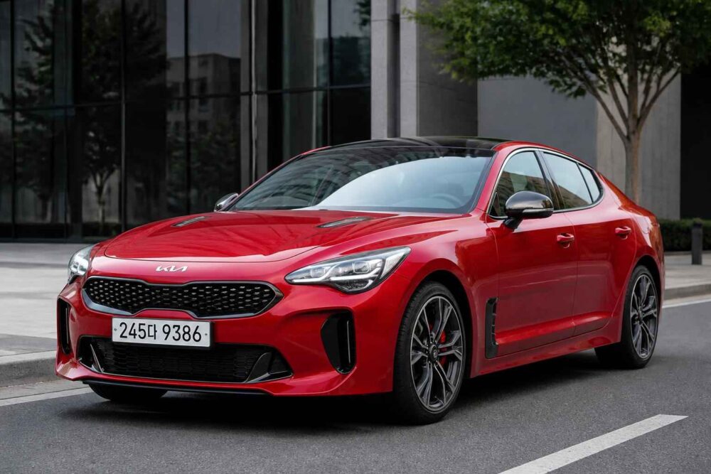 Czerwony sedan Kia Stinger zaparkowany przed nowoczesnym budynkiem miejskim