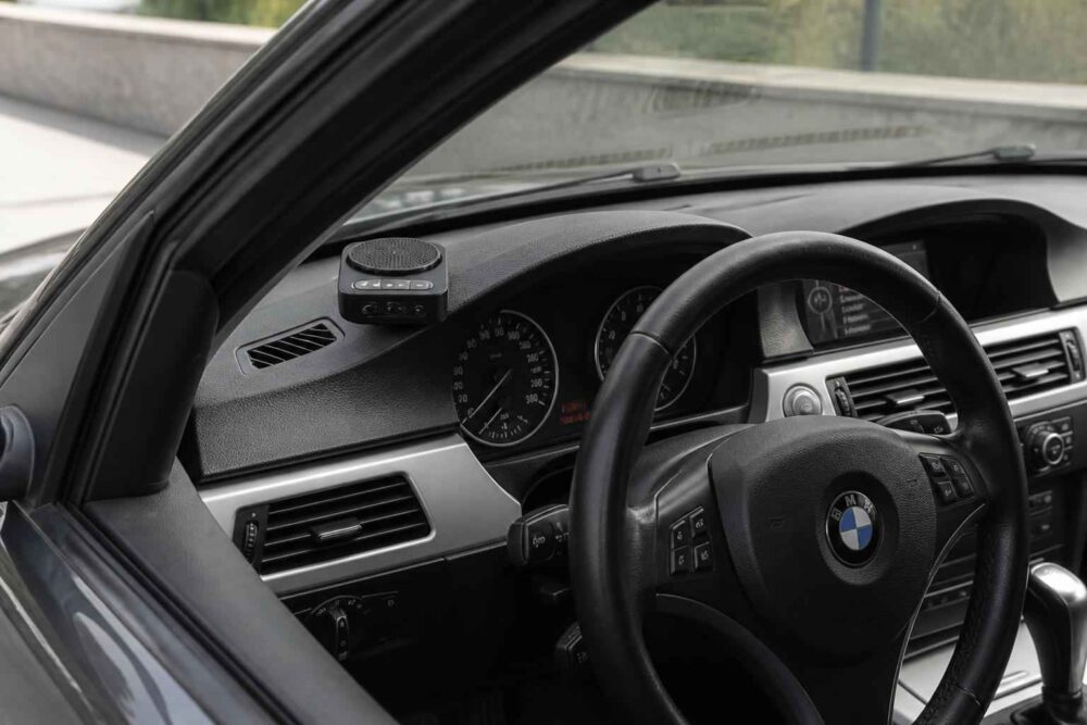 Kokpit BMW z kierownicą po lewej stronie Kokpit BMW z kierownicą, zegarami, nawiewami i konsolą środkową widoczny przez otwarte drzwi