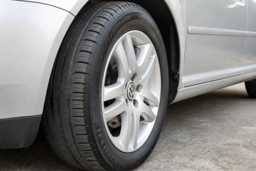 Zbliżenie na przednie koło Volkswagena ze srebrną felgą aluminiową