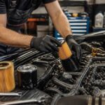 Mechanik w rękawicach montuje filtr oleju w komorze silnika samochodu