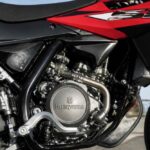 Zbliżenie na silnik i ramę czerwono-czarnego motocykla Husqvarna definiującego techniczny charakter pojazdu